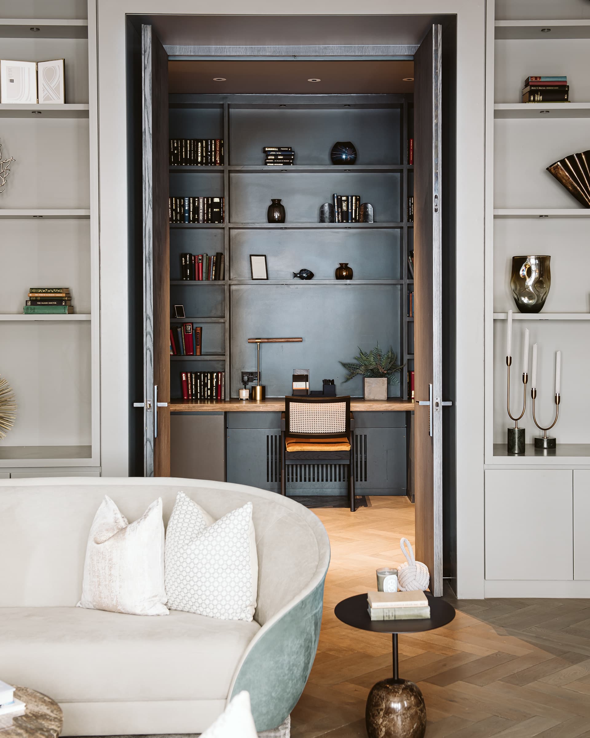Open-plan living room with dark built-in library and herringbone parquet