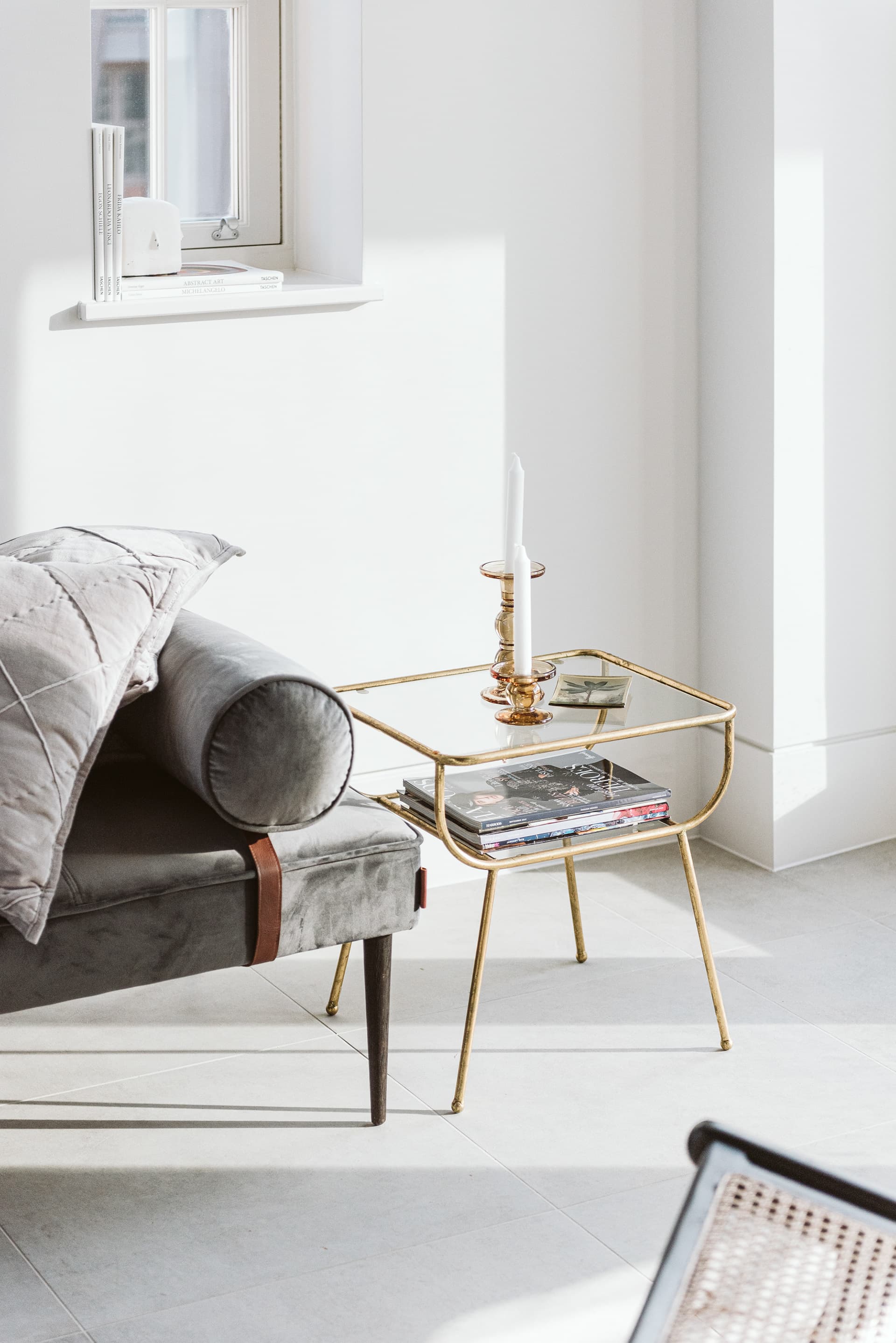 Warehouse loft interior with velvet daybed, brass side table and whitewashed floors