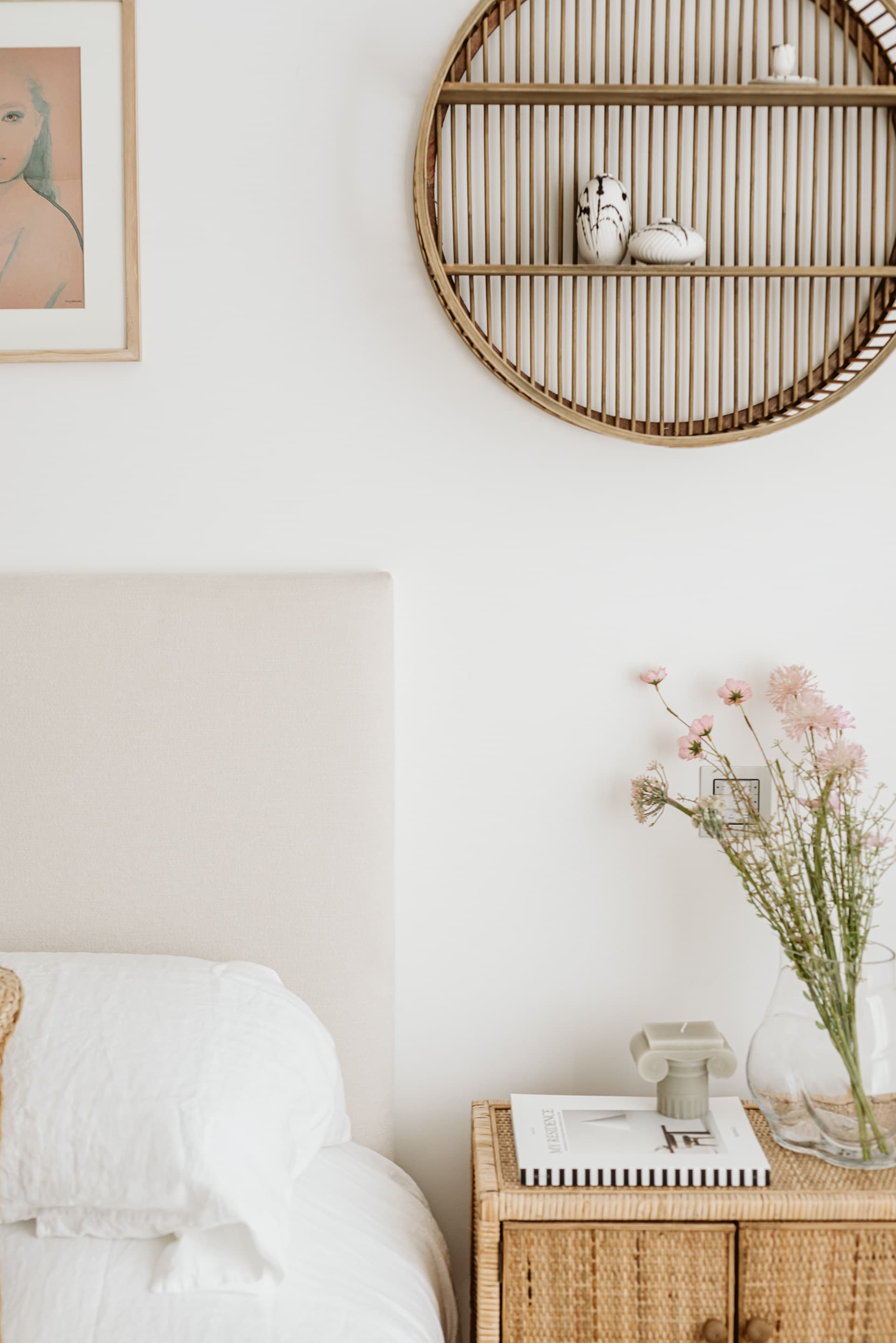 Bedside table with rattan circular shelf and fresh pink flowers