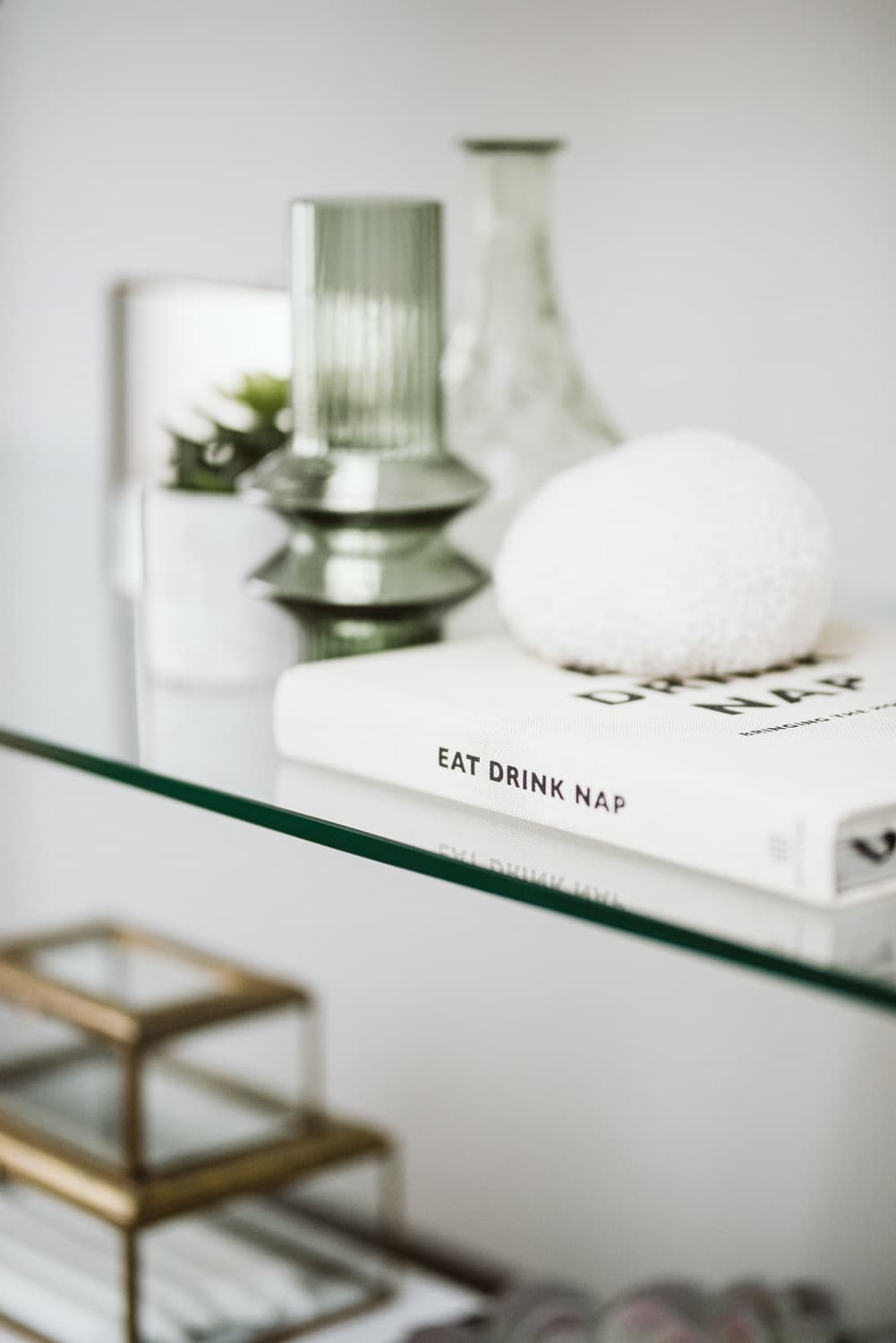 Glass shelf styled with designer ceramics and coffee table book